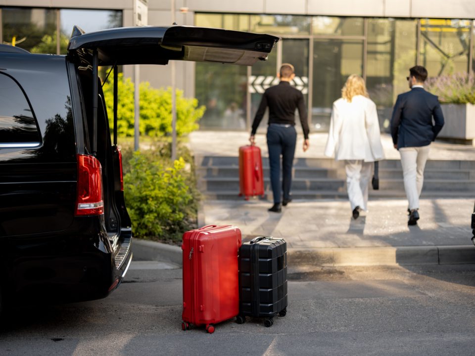 Driver or concierge helps a business couple carry their suitcases to the office or hotel from a minivan taxi. Concept of business travel and transportation service